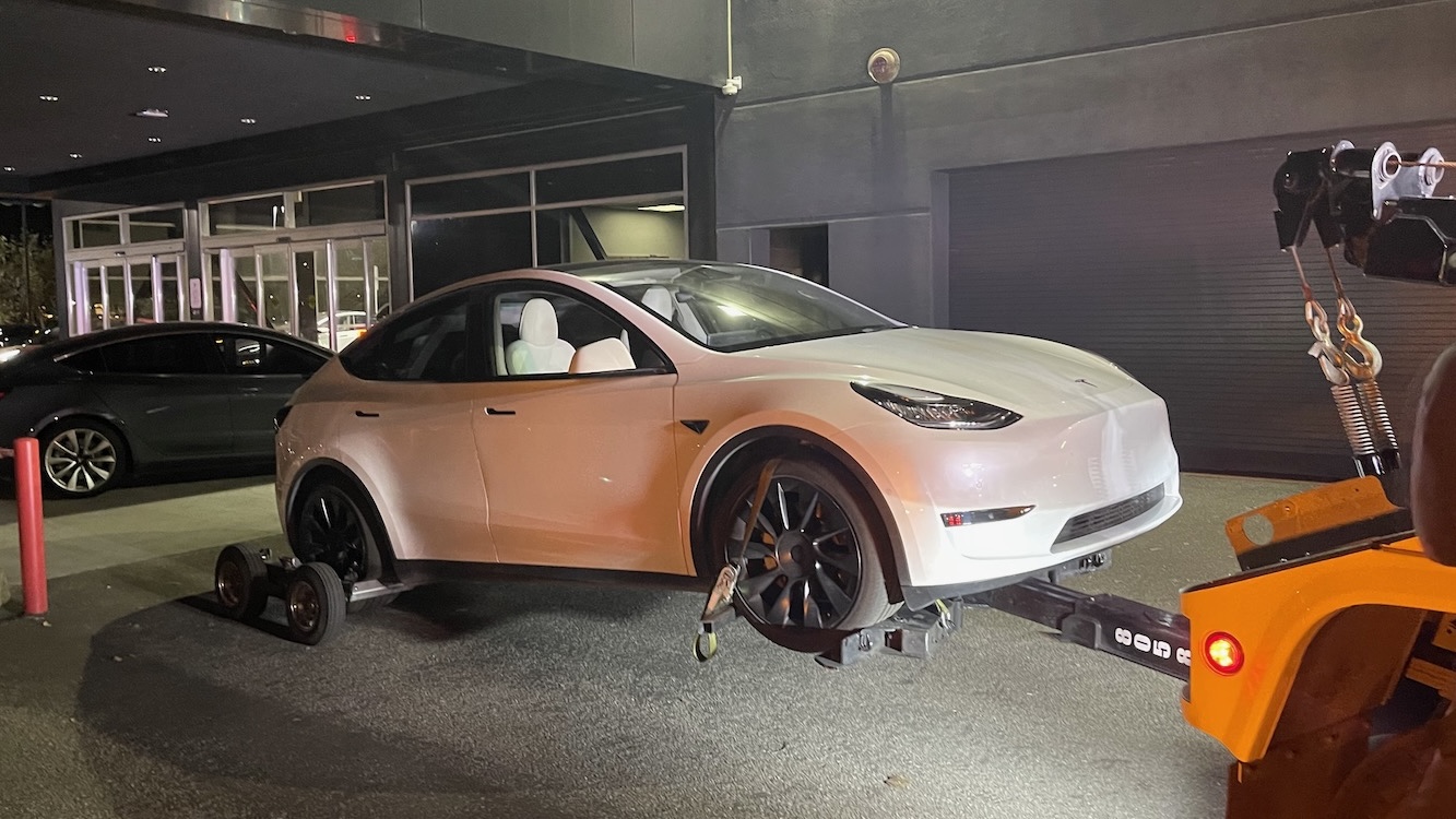 Tesla-bil bliver læsset op på en kranvogn eller bugseret af vejhjælp på en offentlig vej.